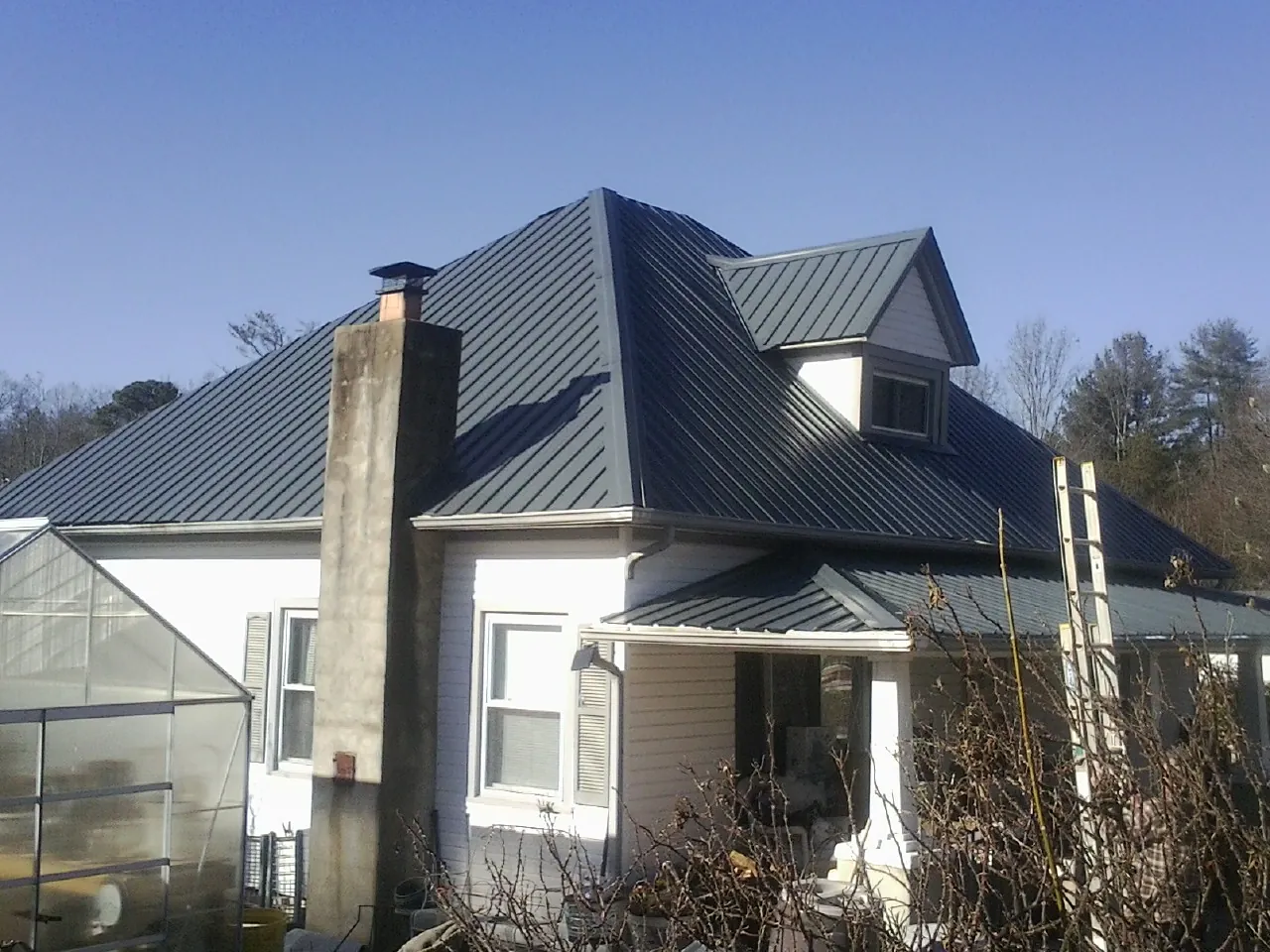Dark blue standing seam metal roof on a white farmhouse with dormer — Slate & Tile Roof Repair by Roofing Brothers in Groton